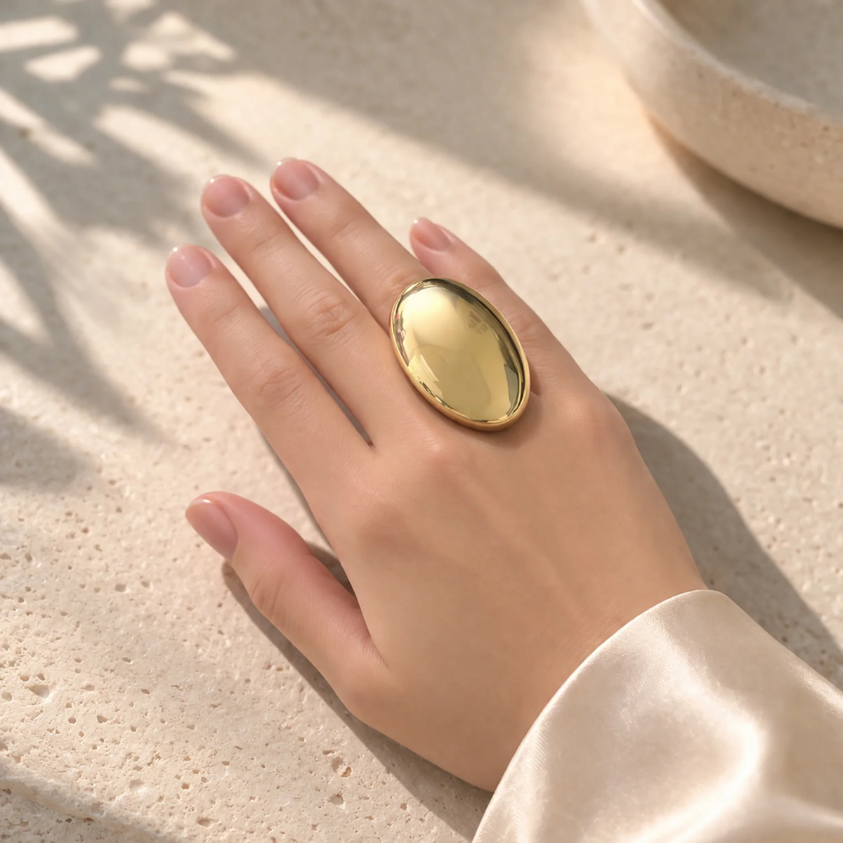 Model wearing a large oval gold-tone ring